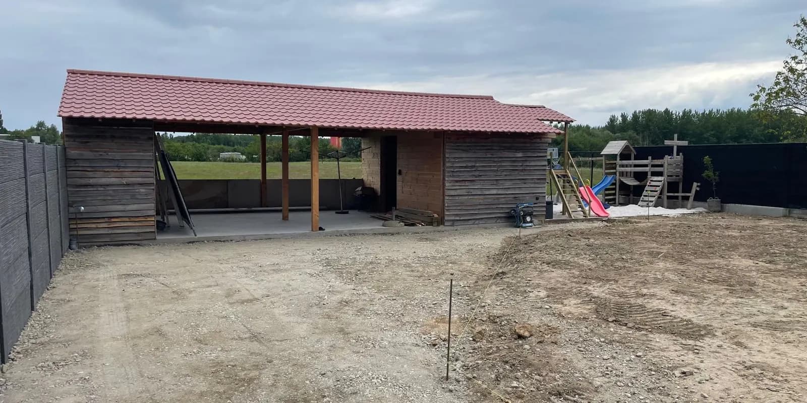 Houten bijgebouw met open overkapping en rode dakpannen