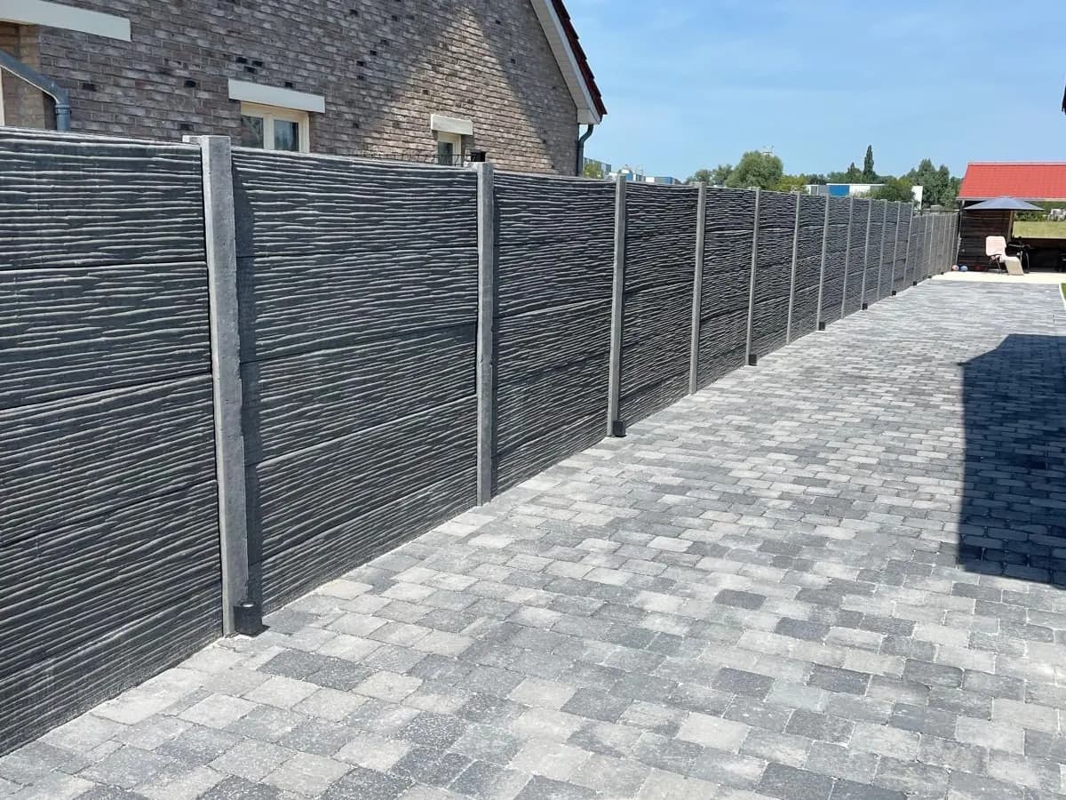 Omheining in betonplaten langs een nieuwe klinkerverharding